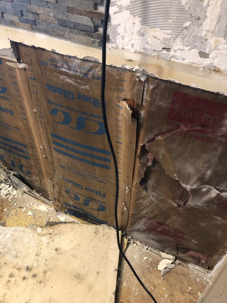 Mold growth on the back of drywall inside a basement wall cavity